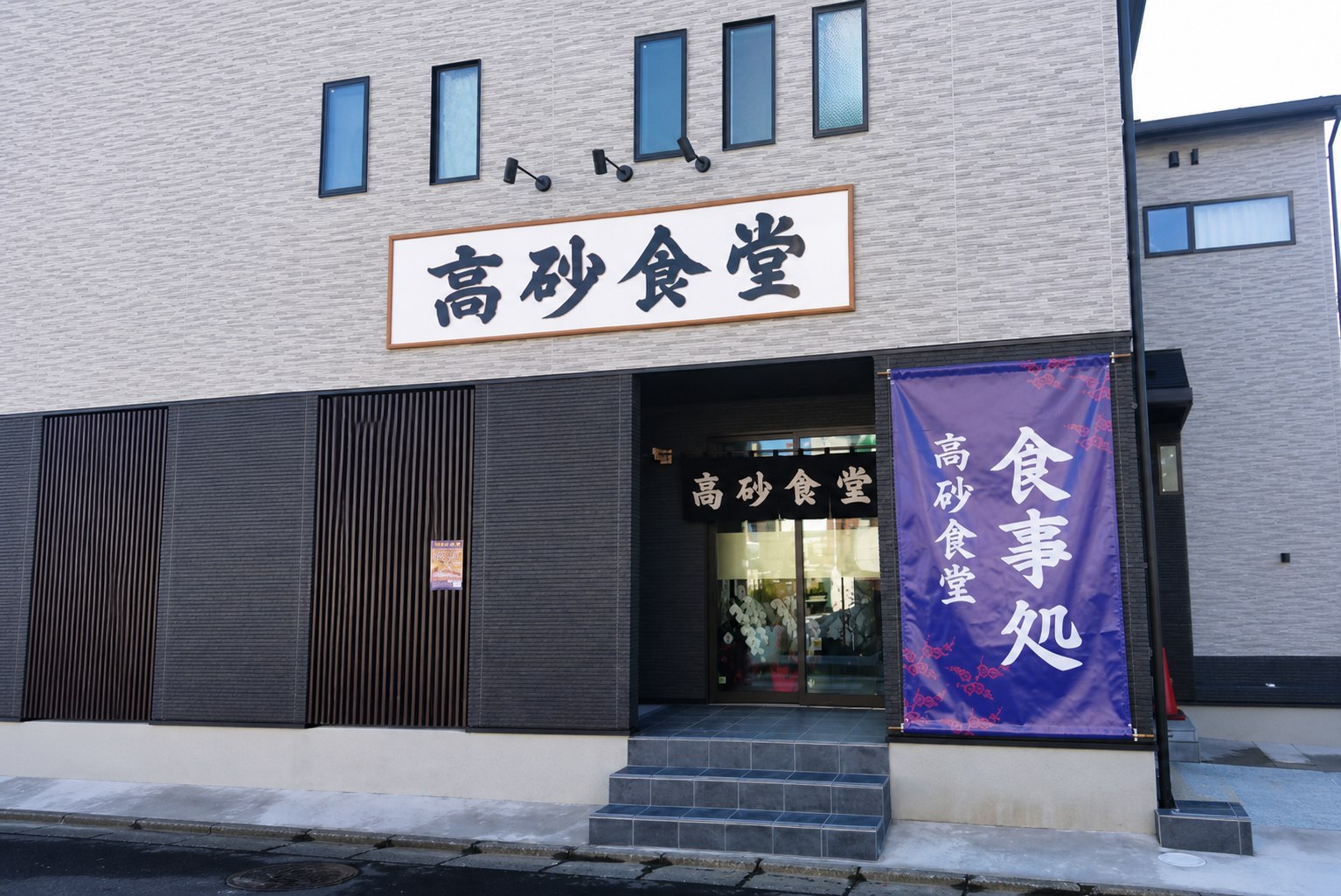 高砂食堂の正面外観と紫色の食事処のぼり